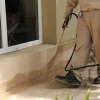 General pest control technician spraying exterior perimeter around a home in Denver, CO