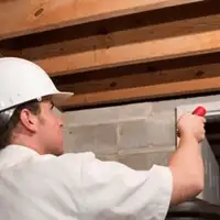 Termite inspection technician checking a basement wall and framing for termite activity in Denver, CO